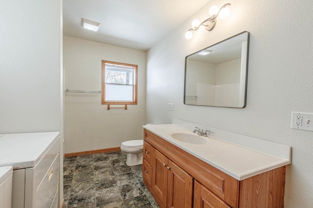 full bathroom featuring stone finish flooring, baseboards, washer and dryer, toilet, and vanity