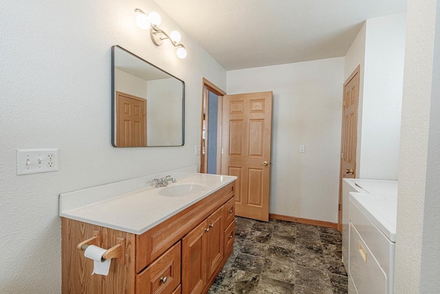 bathroom with vanity, baseboards, washer and clothes dryer, and stone finish floor