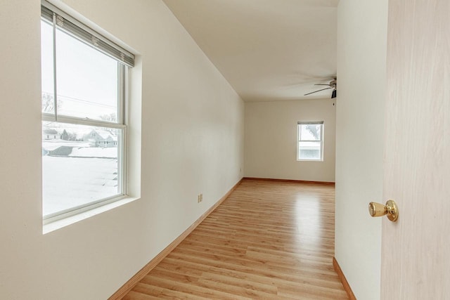 empty room featuring baseboards, a ceiling fan, and light wood finished floors