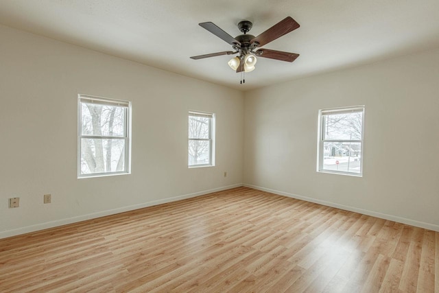 empty room with light wood-type flooring, a ceiling fan, and baseboards