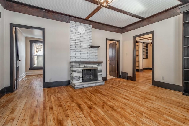 unfurnished living room featuring light wood-type flooring, beamed ceiling, and a fireplace