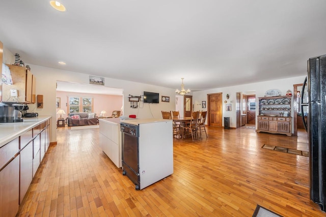 kitchen featuring black appliances, light hardwood / wood-style floors, pendant lighting, white cabinetry, and an inviting chandelier