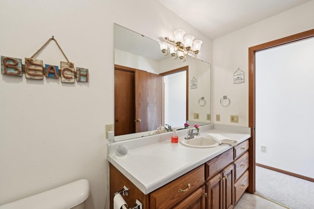 bathroom featuring toilet, vanity, and an inviting chandelier