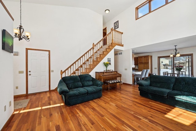 living room featuring light hardwood / wood-style flooring, high vaulted ceiling, and an inviting chandelier