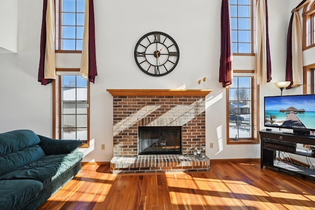 living room with a fireplace, hardwood / wood-style flooring, and a towering ceiling