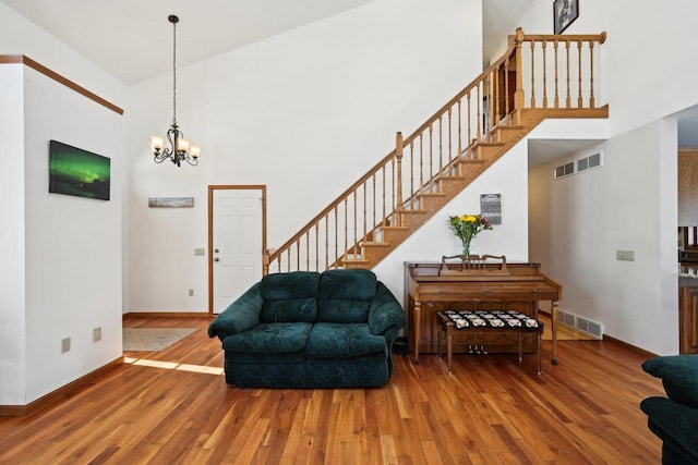 entrance foyer featuring a towering ceiling, a chandelier, and wood-type flooring