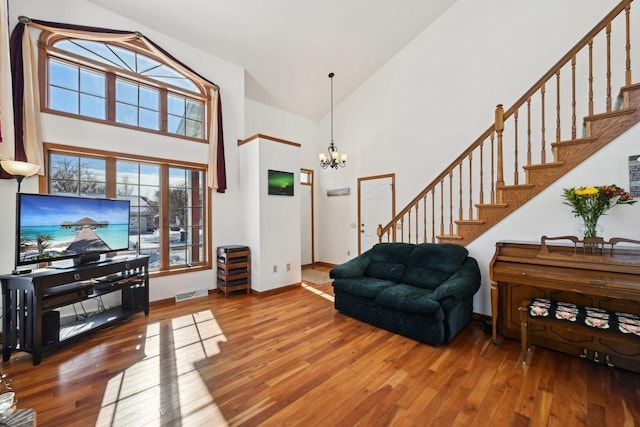 living room featuring high vaulted ceiling, hardwood / wood-style floors, and a chandelier