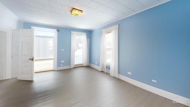 spare room with a healthy amount of sunlight, hardwood / wood-style flooring, and crown molding