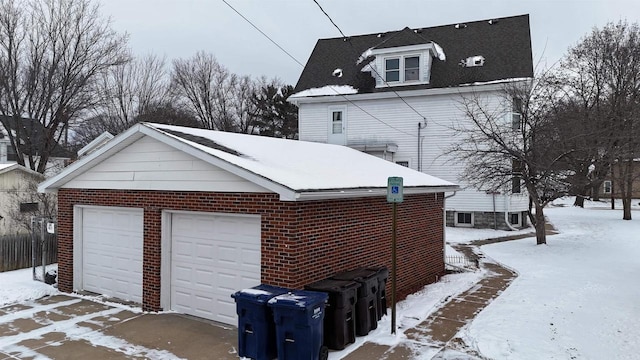 view of snow covered exterior with an outbuilding and a garage