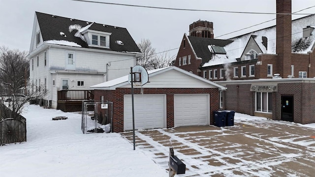 snow covered property featuring a garage and an outdoor structure