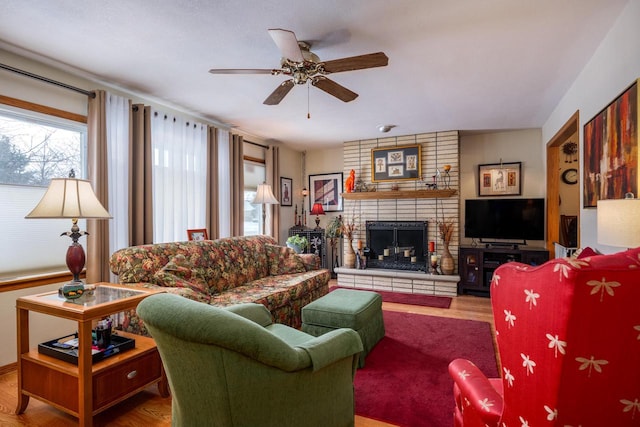 living room featuring a brick fireplace, ceiling fan, and wood-type flooring