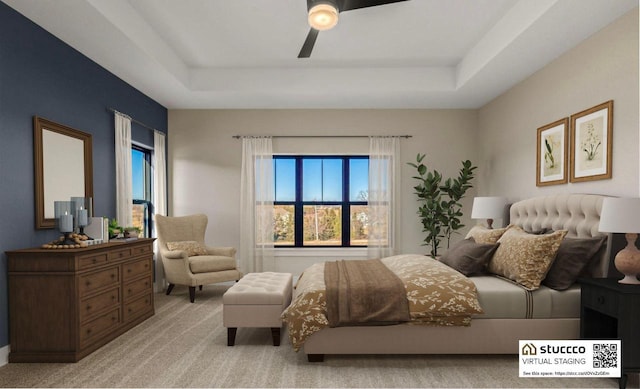 carpeted bedroom with a tray ceiling and ceiling fan