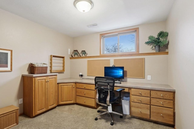 office area with light carpet, visible vents, and built in study area