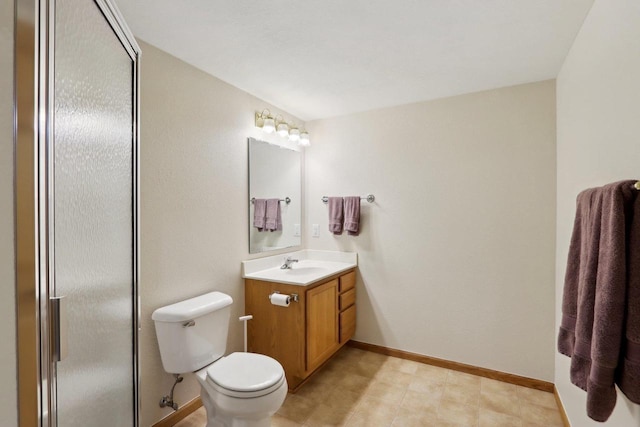 bathroom with toilet, a shower with shower door, baseboards, and vanity