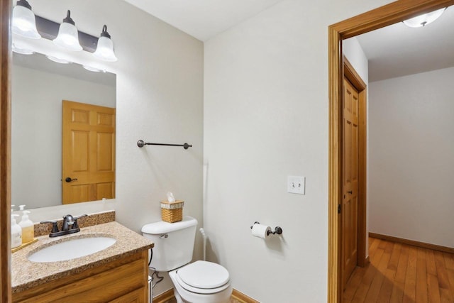 bathroom featuring baseboards, vanity, toilet, and wood finished floors