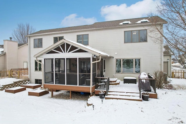 snow covered property featuring a vegetable garden, fence, and a sunroom