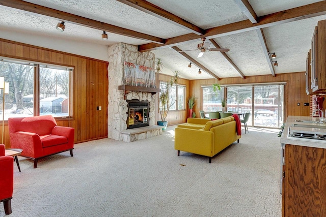 living room featuring a textured ceiling, light carpet, wooden walls, and a wealth of natural light