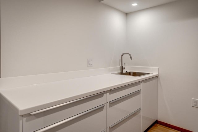 laundry area featuring sink and light hardwood / wood-style floors