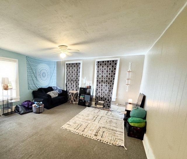 living area featuring a ceiling fan, carpet, and a textured ceiling