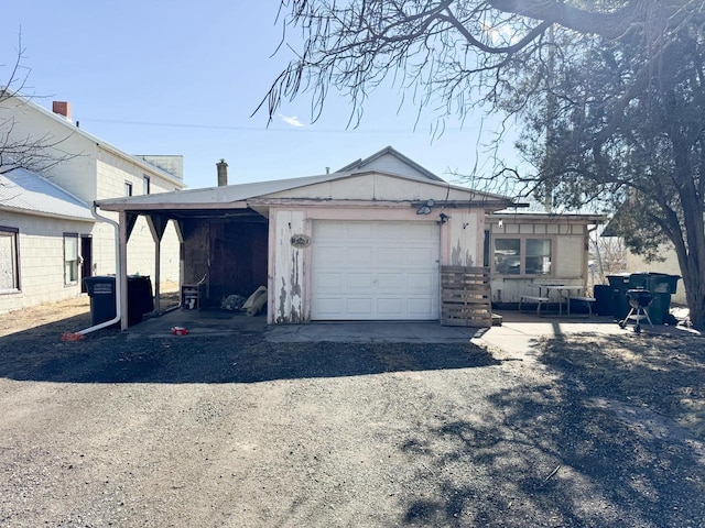 view of front facade with a garage, dirt driveway, and a carport