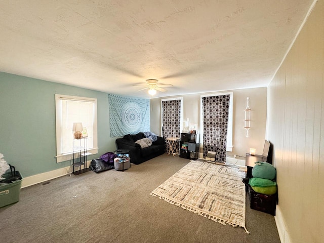 sitting room featuring carpet floors, ceiling fan, baseboards, and a textured ceiling