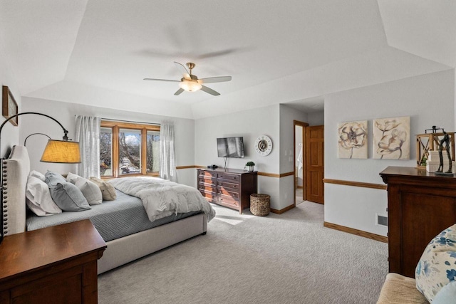 bedroom with light carpet, ceiling fan, and a tray ceiling