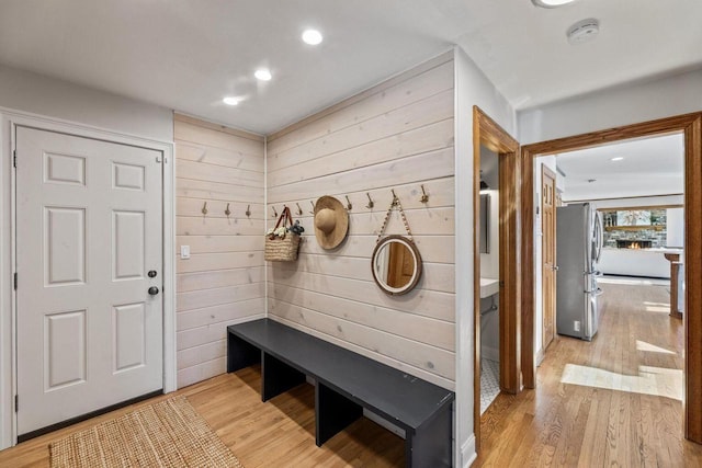 mudroom featuring light hardwood / wood-style floors and wooden walls