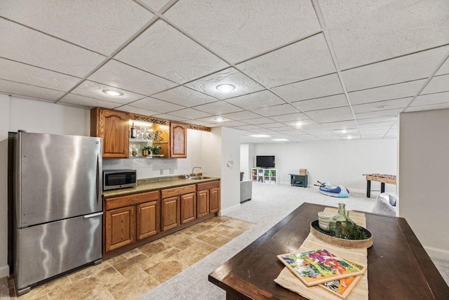 kitchen with sink, stainless steel appliances, light carpet, and a paneled ceiling