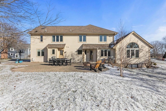 snow covered back of property with a patio area and a fire pit