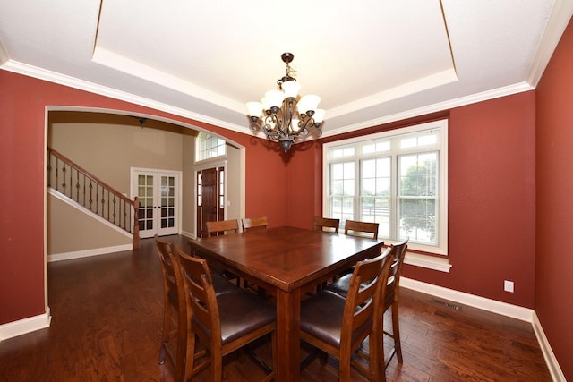 dining area with arched walkways, french doors, a raised ceiling, dark wood-type flooring, and baseboards