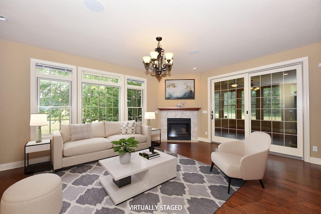 living room featuring dark wood-style floors, an inviting chandelier, a glass covered fireplace, and baseboards