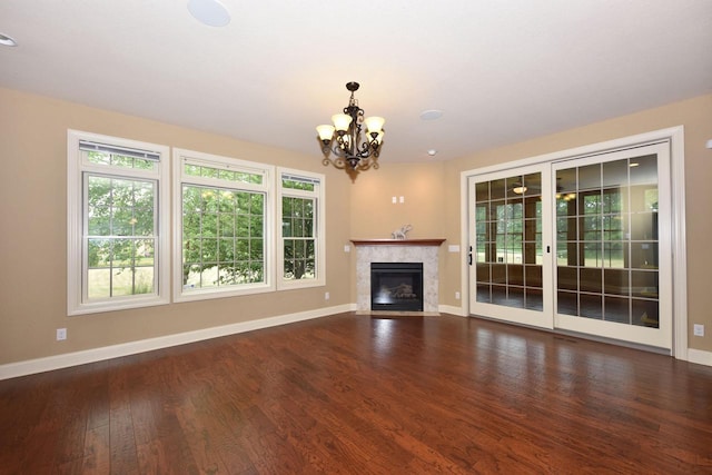 unfurnished living room featuring a chandelier, dark wood-type flooring, a fireplace, and baseboards