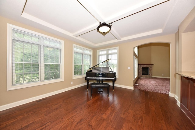 living area featuring arched walkways, a fireplace, visible vents, baseboards, and dark wood-style floors