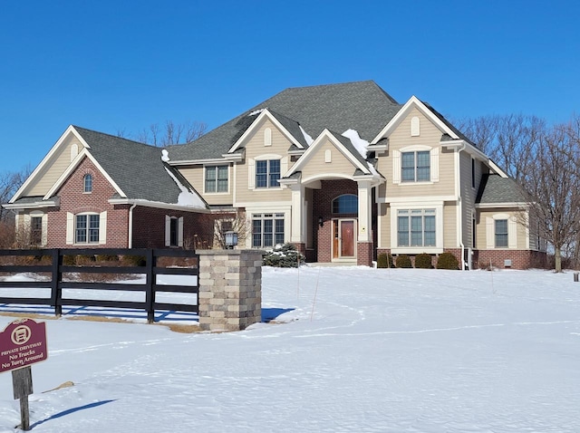 view of front of home featuring brick siding, a shingled roof, and fence