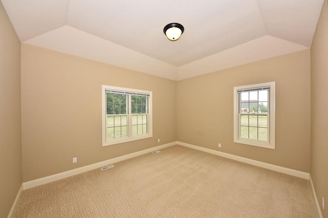 unfurnished room with lofted ceiling, baseboards, visible vents, and light colored carpet