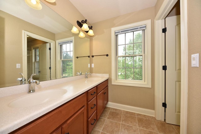 bathroom featuring tile patterned flooring, a sink, baseboards, and double vanity