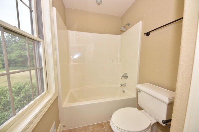 bathroom with toilet, tile patterned flooring, washtub / shower combination, and a wealth of natural light