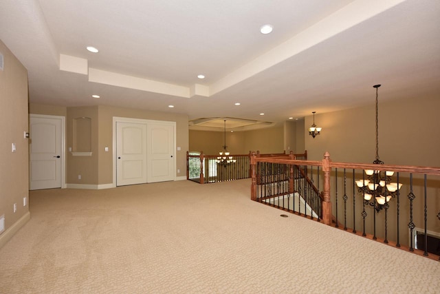 carpeted empty room featuring a tray ceiling, a notable chandelier, baseboards, and recessed lighting