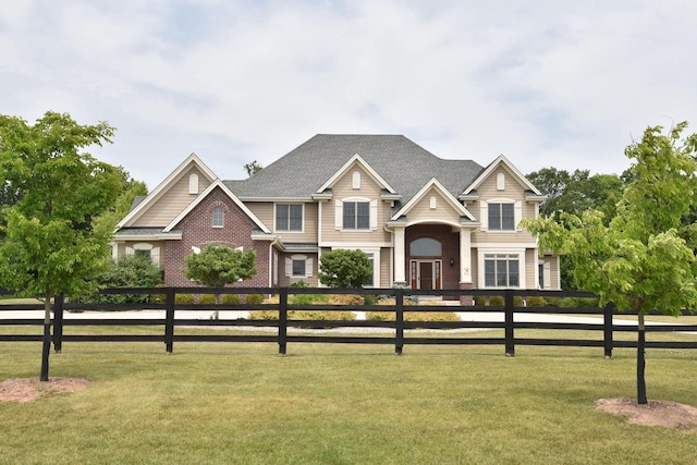 view of front facade featuring a fenced front yard, roof with shingles, and brick siding