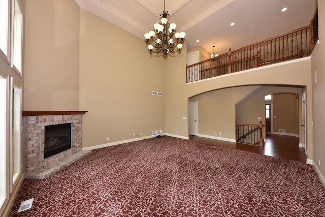 unfurnished living room featuring baseboards, visible vents, arched walkways, and carpet flooring