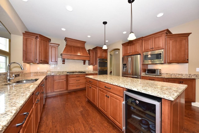 kitchen with wine cooler, custom exhaust hood, appliances with stainless steel finishes, a sink, and a kitchen island