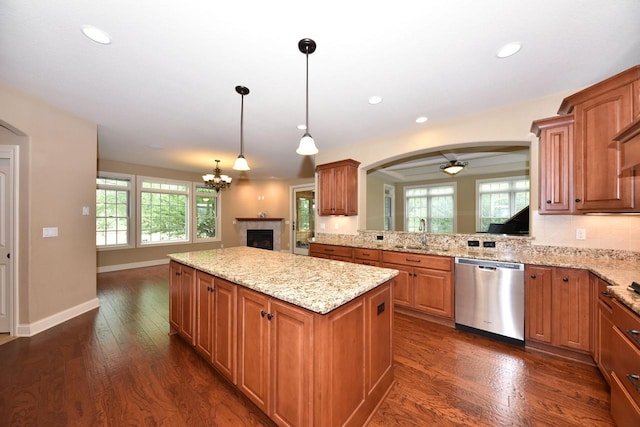 kitchen featuring dishwasher, a kitchen island, dark wood-type flooring, decorative light fixtures, and a sink