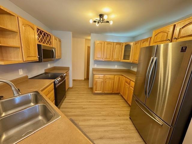 kitchen featuring sink, an inviting chandelier, stainless steel appliances, and light hardwood / wood-style floors