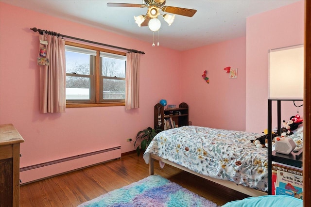 bedroom featuring hardwood / wood-style floors, baseboard heating, and ceiling fan