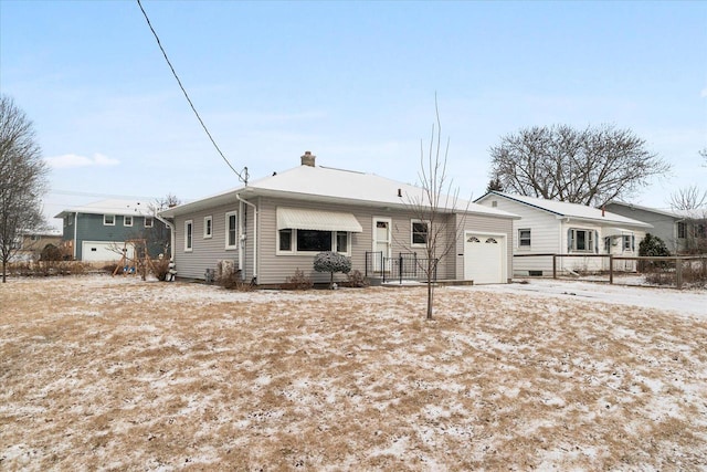 view of front of house with a chimney, an attached garage, and fence