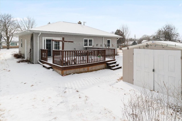 snow covered property with a storage shed and a wooden deck