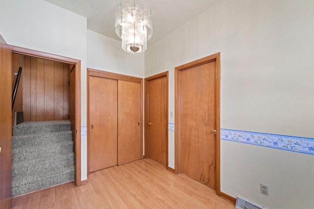 corridor featuring light wood-type flooring and a notable chandelier