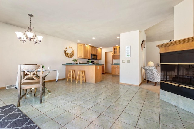 kitchen with an inviting chandelier, light tile patterned floors, pendant lighting, a kitchen breakfast bar, and kitchen peninsula