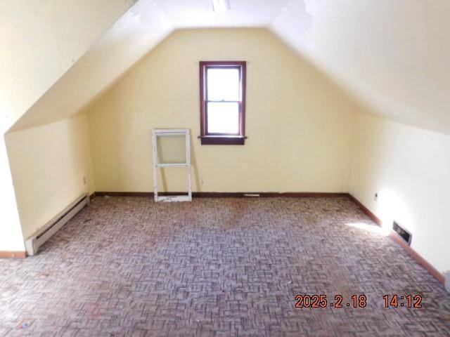 additional living space with a baseboard radiator, vaulted ceiling, and carpet flooring