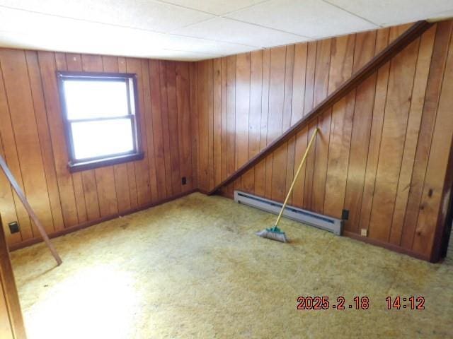 spare room with light carpet, baseboard heating, and wooden walls